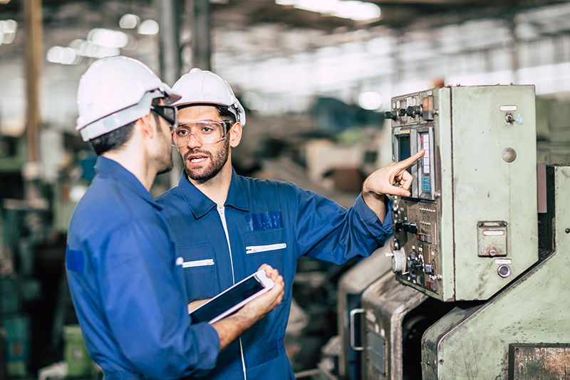 Engineer teamwork checking control panel and teaching new worker to operating control the machine in factory.